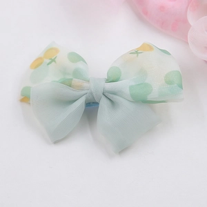 Nahaufnahme der minzgrünen Haarschleife aus Chiffon mit Kirsch- und Herzmustern