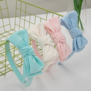Detail showing four colors of striped cotton bow headbands in mint, cream, pink and blue