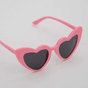 Close-up of heart-shaped kids sunglasses in bright pink frame with 45-degree angle view