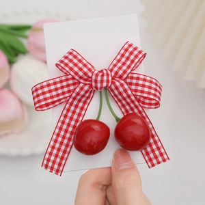 Detailed macro view of girls cherry bow hair clip with red and white gingham fabric