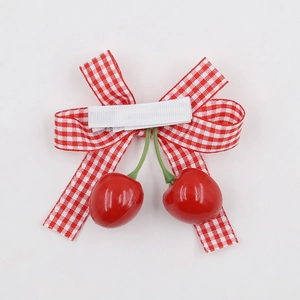 Close-up of kids red cherry bow hair clip with red and white gingham pattern ribbon