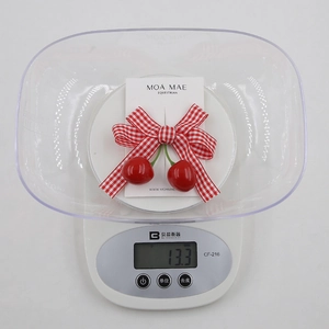 Detail view of red checkered bow hair clip with cherry charms weighing 13.3 grams