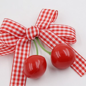 Detailed view of red and white checkered bow with shiny cherry pendants for girls