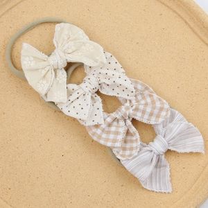 Detail of 4-pack baby headbands with floral embroidery, polka dots, and plaid patterns