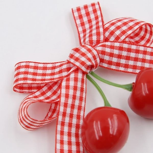 Close-up of red and white checkered bow hair clip with cherry charms and green leaves