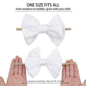 Stretchy white baby bow headband showing one size fits all flexibility for newborns to toddlers