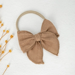 Détail du bandeau bébé avec texture en lin camel sur une boucle en nylon élastique souple