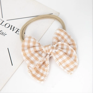 Detailed view of baby headband with a brown gingham bow and soft nylon elastic band