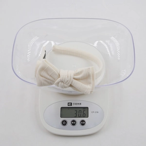 Detail shot of a cream striped cotton headband for girls weighing 30.6g on a digital scale