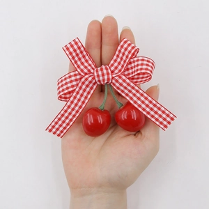 Close-up of kids red gingham bow hair clip with glossy artificial cherry pendants