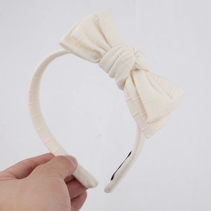 Detailed texture of a double-layered cream cotton bow on a minimalist girls headband