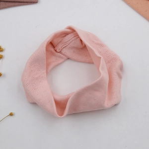 Close-up of pink pointelle knit yoga headband showing detailed cross knot fabric texture
