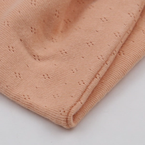 Close-up of peach pointelle knit yoga headband showing breathable mesh and soft texture