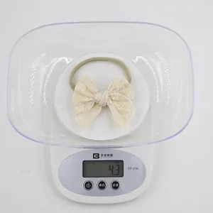 Detailed close-up of lightweight embroidered lace bow headband weighing 4.3g on a scale