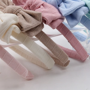 Detail of knitted bow headbands in five pastel colors on clear acrylic stands