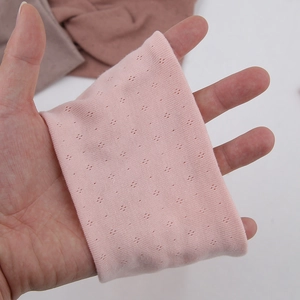Detail of pink knitted yoga headband showing elastic texture and hollow dot pattern
