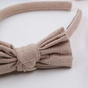 Close-up of beige knitted headband featuring heart patterns and striped texture bow