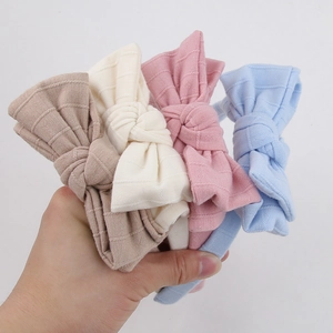 Detail of four striped cotton bow headbands for girls in khaki, beige, pink, and sky blue