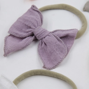 Détail du nœud en gaze violette avec bandeau élastique en nylon vert olive pour bébé