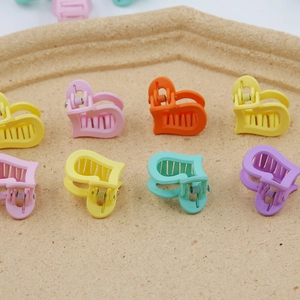 Détail de mini pinces à cheveux en forme de cœur aux couleurs pastel sur un plateau