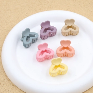 Dettaglio di 6 mini mollette a cuore opaco colorato in un vassoio bianco per bambine