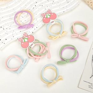 Détail d'élastiques à cheveux colorés pour enfants avec nœud et emballage motif cerise
