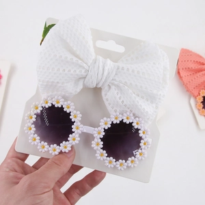 Detail view of white lace bow headband and daisy floral sunglasses set for kids