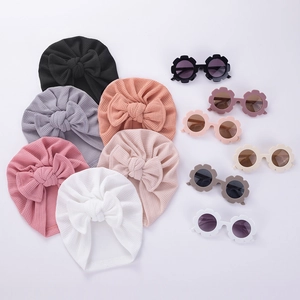 Détail d'un turban bébé en tissu gaufré avec nœud et lunettes fleur de soleil