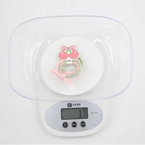 Détail d'élastiques cerise rose et vert sur une balance indiquant un poids de 3,7g