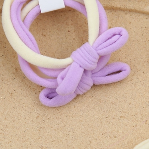 Détail de chouchous nœuds élastiques en tricot doux coloris violet et beige clair