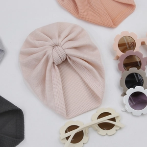Gros plan d'un bonnet turban rose gaufré pour bébé avec lunettes de soleil fleurs