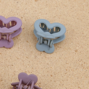 Dettaglio di fermagli per capelli a forma di cuore viola e blu opaco su fondo in sughero