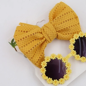 Close-up of yellow mesh bow headband and daisy floral sunglasses for children summer set