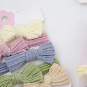 Detailed macro view of five colorful corduroy bow hair ties on white card packaging