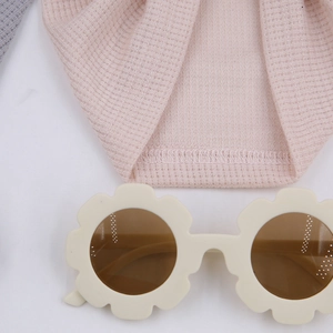 Détail du tissu gaufré rose et des lunettes de soleil fleurs pour enfants