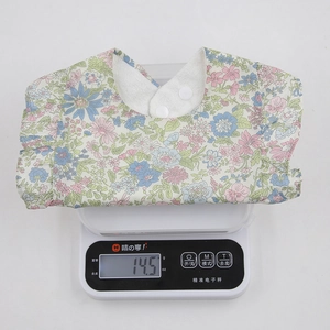 Détail d'un bavoir floral léger pour bébé avec bords à volants sur une balance blanche