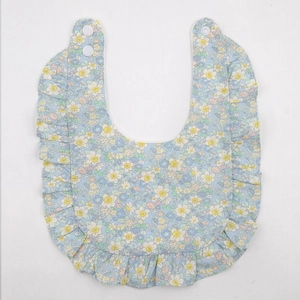 Détail d'un bavoir floral pour bébé avec bords à volants et double bouton-pression