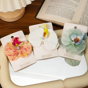Detail view of orchid hair clips with pearls on elegant display card and mirror