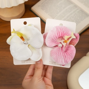 Close-up of white and pink orchid hair clips with pearls on a card holder