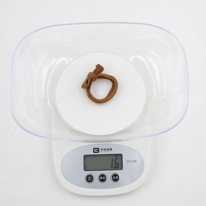 Detailed view of a 1.6g brown bow hair tie on a digital scale for weight verification