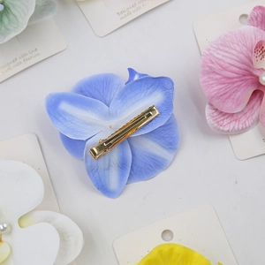 Macro view of orchid flower hair clips with golden metal clamps and pearl centers