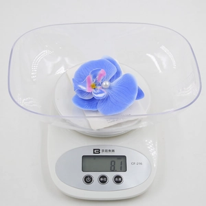 Detailed top view of realistic blue orchid hair clip with pearl on a digital scale weighing 8.1g