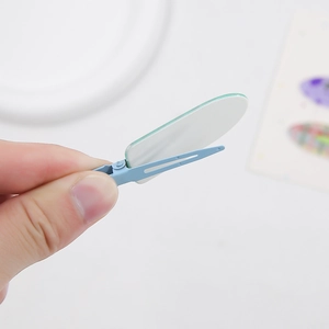 Pince à cheveux en acétate bleu clair avec détail ovale tenue à la main