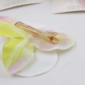 Detailed view of the metal alligator clip on the back of a realistic orchid flower hair clip