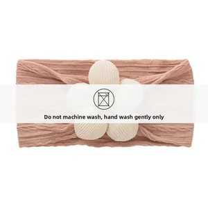 Gros plan du bandeau tricoté pour bébé avec fleur 3D et instructions de lavage à la main