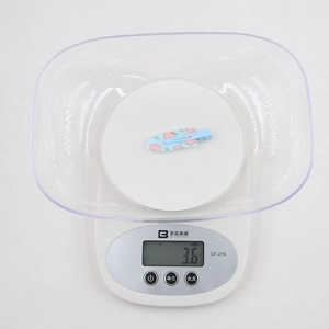 Détail d'une pince à cheveux légère de 3,6g avec motif de pêche sur une balance