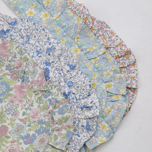 Détail de quatre bavoirs bébé en coton floral avec bords à volants et boutons-pression