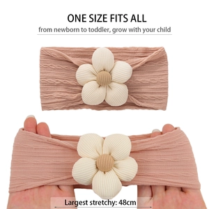 Détail du bandeau tricoté pour bébé montrant l'élasticité et la fleur en tissu