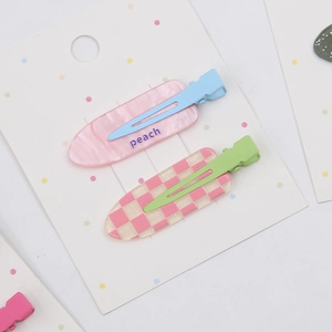 Détail d'une pince pêche en marbre rose et d'épingles à damier sur carte cadeau