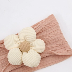 Détails de la maille douce et de la grande fleur crème sur le bandeau rose pour bébé